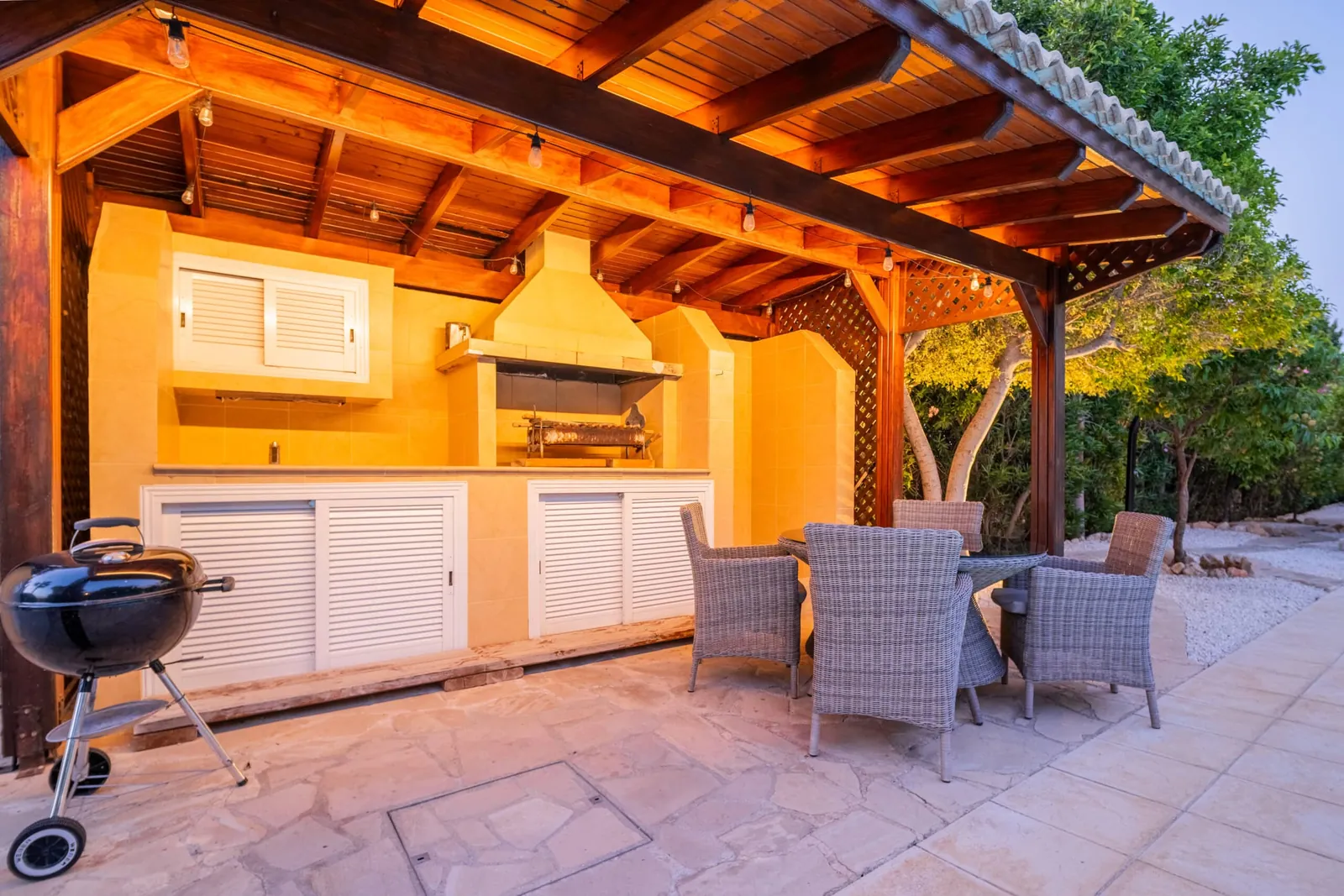 Outdoor kitchen with Weber and foukou souvlaki grill and dining table for four.