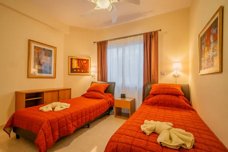Red bedroom with two twin beds (can be pushed together to form a king bed). Veiling fan, dedicated AC/heating unit, large built-in wardrobes, bluetooth speaker/alarm clock. Views of the garden. Full bathroom in hallway.