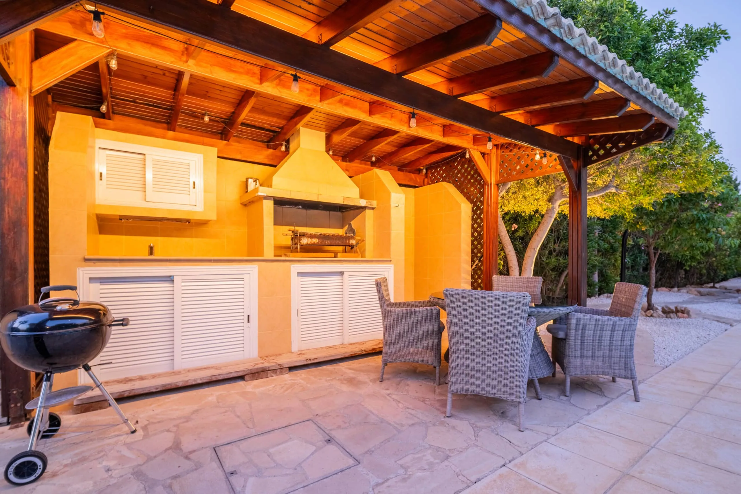 Outdoor kitchen with Weber and foukou souvlaki grill and dining table for four.